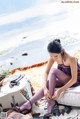 A woman sitting on top of a bed next to the ocean.