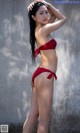 A woman in a red bikini standing in the water.