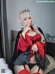 A woman dressed as a vampire sitting on a bed.