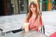 A woman sitting at a table with a drink in her hand.