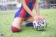 A woman sitting on the ground with a soccer ball.