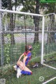 A woman wearing a face mask sitting in front of a soccer goal.