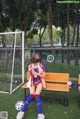 A woman sitting on a bench with a soccer ball.