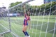 A woman standing in front of a soccer goal on a field.