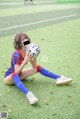 A woman sitting on the ground holding a soccer ball.