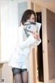 A woman in a white jacket and black stockings holding a magazine.