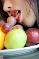 A woman sticking out her tongue in front of a plate of fruit.