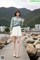 A woman in a white skirt and a green sweater posing for a picture.