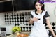 A woman in a maid outfit is posing in the kitchen.