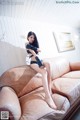 A woman sitting on top of a brown couch.