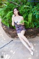 A woman sitting on a stone wall in a dress.