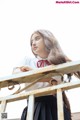 A woman in a school uniform leaning on a railing.