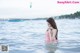 A woman in a pink bathing suit standing in the water.