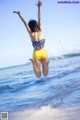 A woman jumping in the air on a beach.