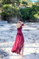 A woman in a red dress standing on a beach.