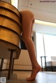 A woman is sitting on top of a wooden barrel.