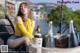 A woman sitting on top of a wooden bench next to a bottle of beer.