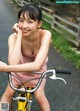 A young woman riding a yellow bike on a road.