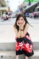 A woman sitting on the steps of a city street talking on a cell phone.