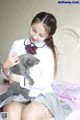 A woman in a school uniform holding a gray cat.