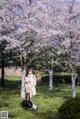 A woman standing in front of a tree with pink flowers.