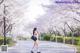 A woman walking down a path lined with cherry blossoms.