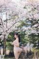 A woman standing in front of a tree with pink flowers.