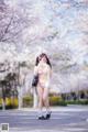 A woman in a white lingerie standing in front of a tree.