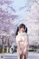 A woman in lingerie posing in front of a flowering tree.