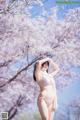 A woman in a pink bikini standing in front of a tree.