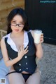 A woman in a black and white dress holding a glass of milk.