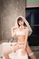 A woman in a white lingerie sitting in a bathtub.