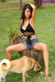 A woman sitting on top of a tree stump next to a dog.