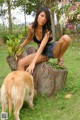 A woman sitting on top of a tree stump next to a dog.