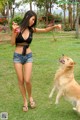 A woman in shorts and a black top playing with a dog.