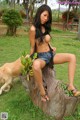 A woman sitting on top of a tree stump next to a dog.