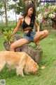 A woman sitting on top of a tree stump next to a dog.