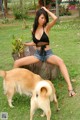 A woman sitting on top of a tree stump next to a dog.