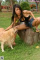 A woman sitting on a tree stump next to a dog.