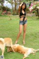 A woman standing next to two dogs in a grassy area.