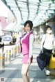 A woman in a pink suit talking on a cell phone.