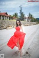 A woman in a red dress is walking on the beach.