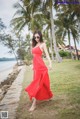 A woman in a red dress walking on the beach.