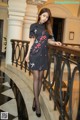 a woman in a black dress standing on a balcony