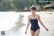 A woman in a blue swimsuit walking on the beach.