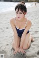 A woman in a blue and white bathing suit sitting on a beach.