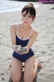 A woman in a blue bathing suit sitting on a beach.