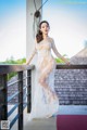 A woman in a white dress standing on a balcony.