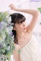 A woman in a white dress leaning against a white railing.