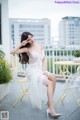 A woman in a white dress sitting on a chair.